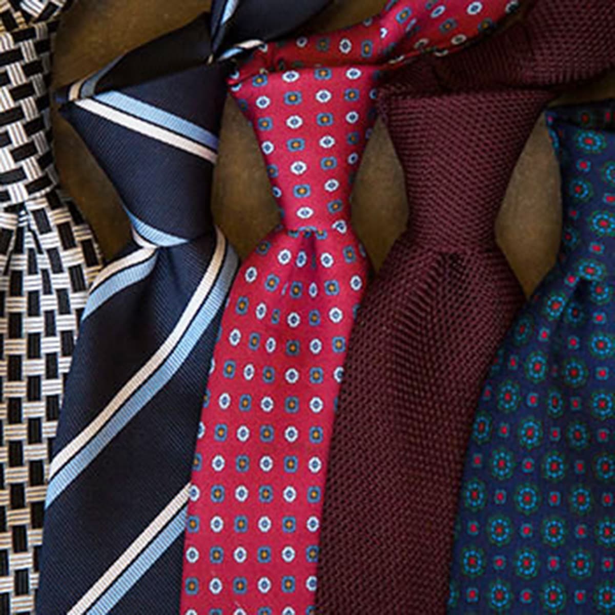 Photo of an assortment of blue striped and red and blue patterned mens neck ties.