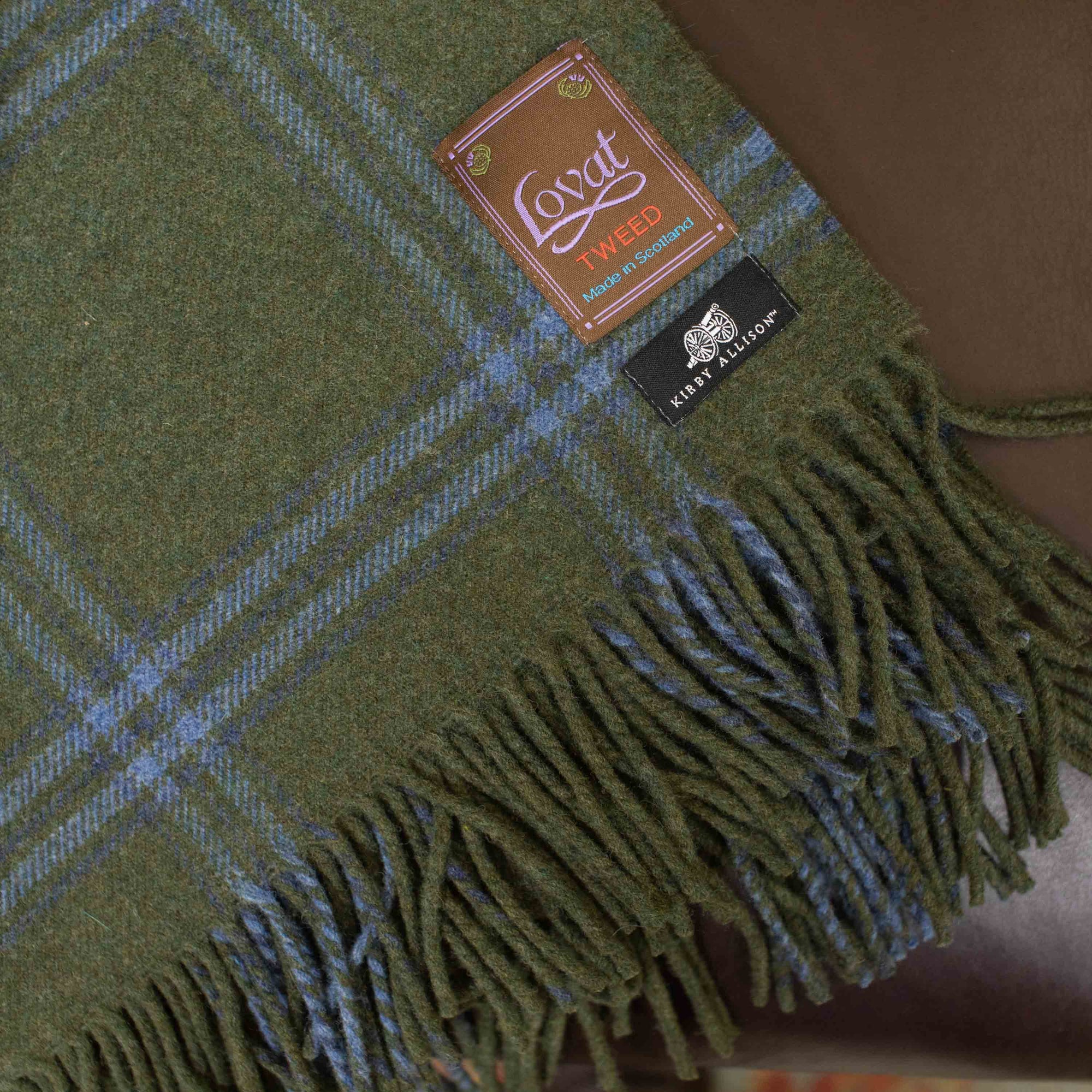 A Lovat Mill Kirby Allison Suit to Shoot Tweed Wool Throw on a leather couch.