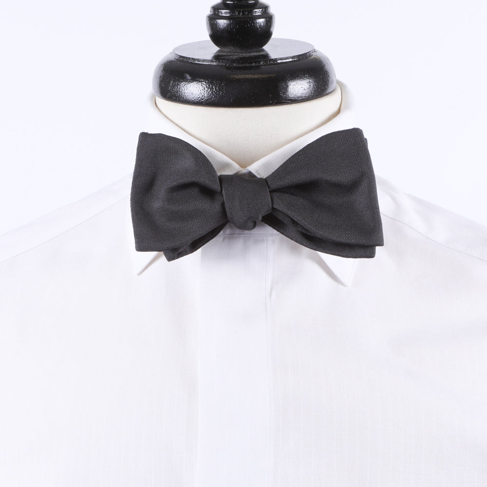 A Sovereign Grade Black Barathea Bow Tie from KirbyAllison.com on a white shirt mannequin for a formal occasion.