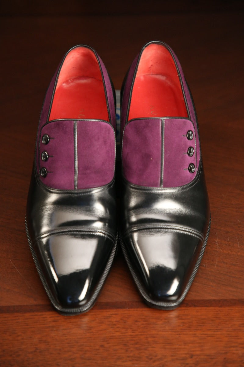 A pair of black shoes on a wooden table, showcasing their KirbyAllison.com High Shine Service.