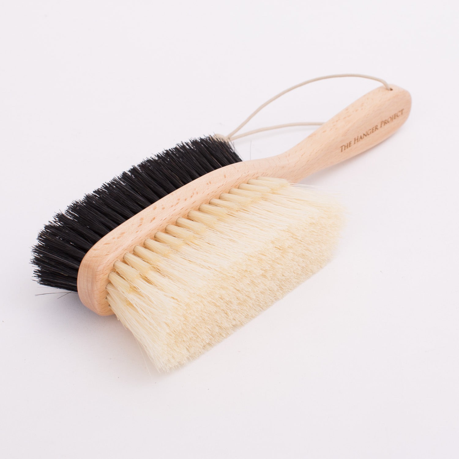 A KirbyAllison.com Deluxe Double-Sided Garment Brush with black and white bristles.