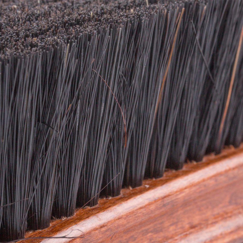 A close up of a Deluxe Wellington Pig Bristle Shoe Polishing Brush from KirbyAllison.com on a wooden surface used for shoe polishing.