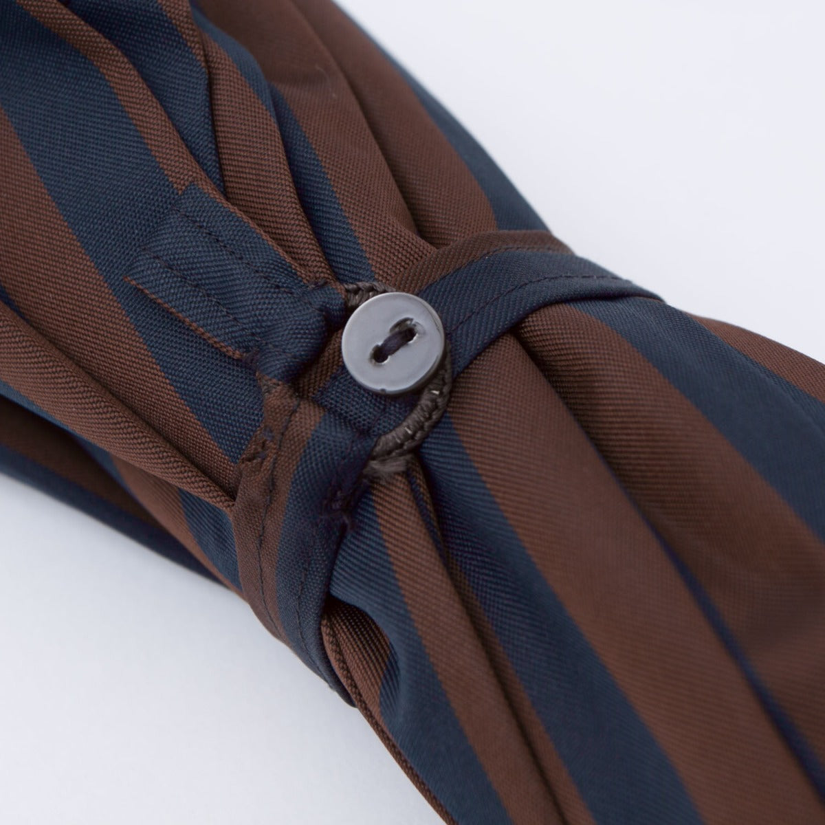 A Navy and Brown Stripe Travel Umbrella with Leather Handle from KirbyAllison.com with a button.