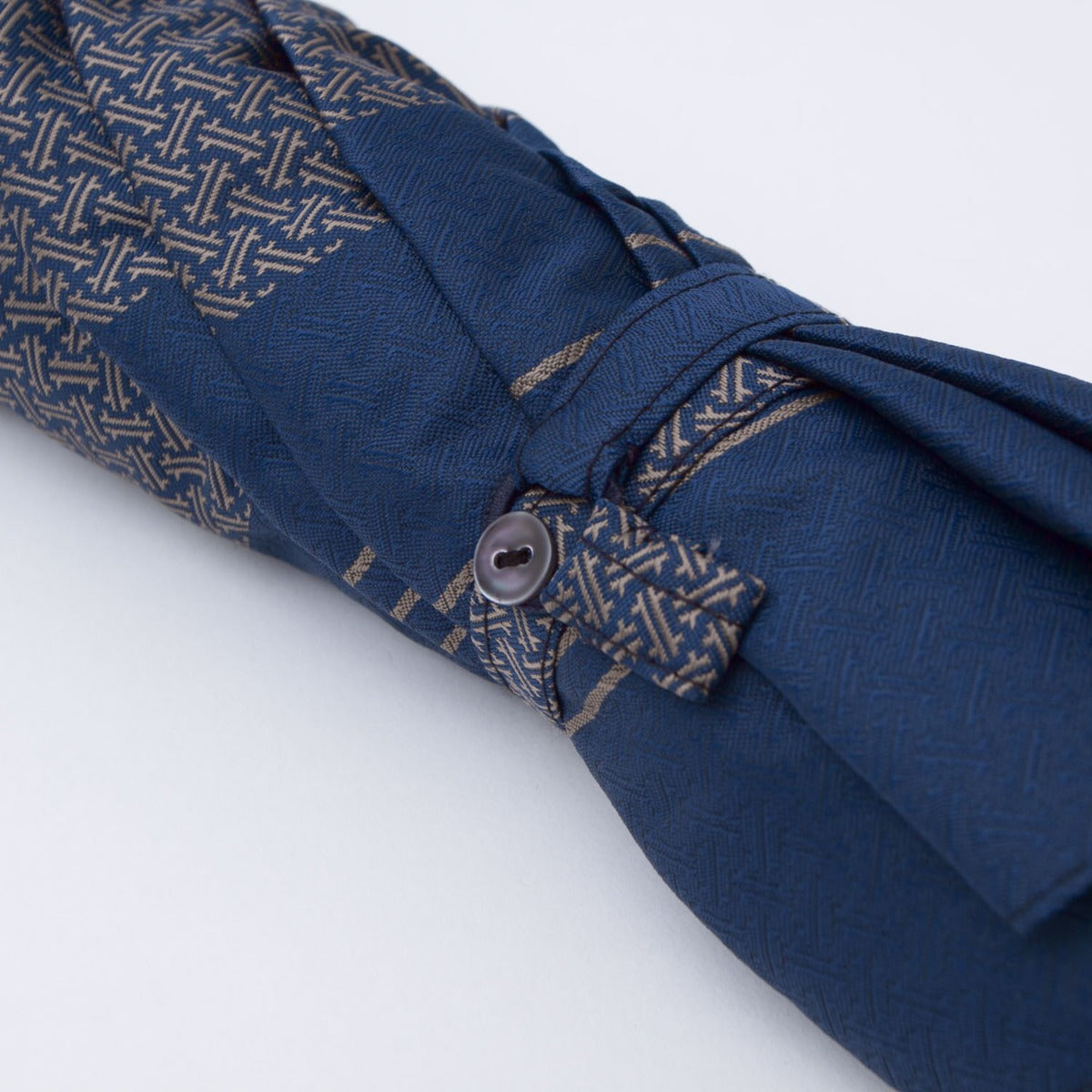 A Patterned Navy Travel Umbrella with Leather Handle by KirbyAllison.com on a white surface.