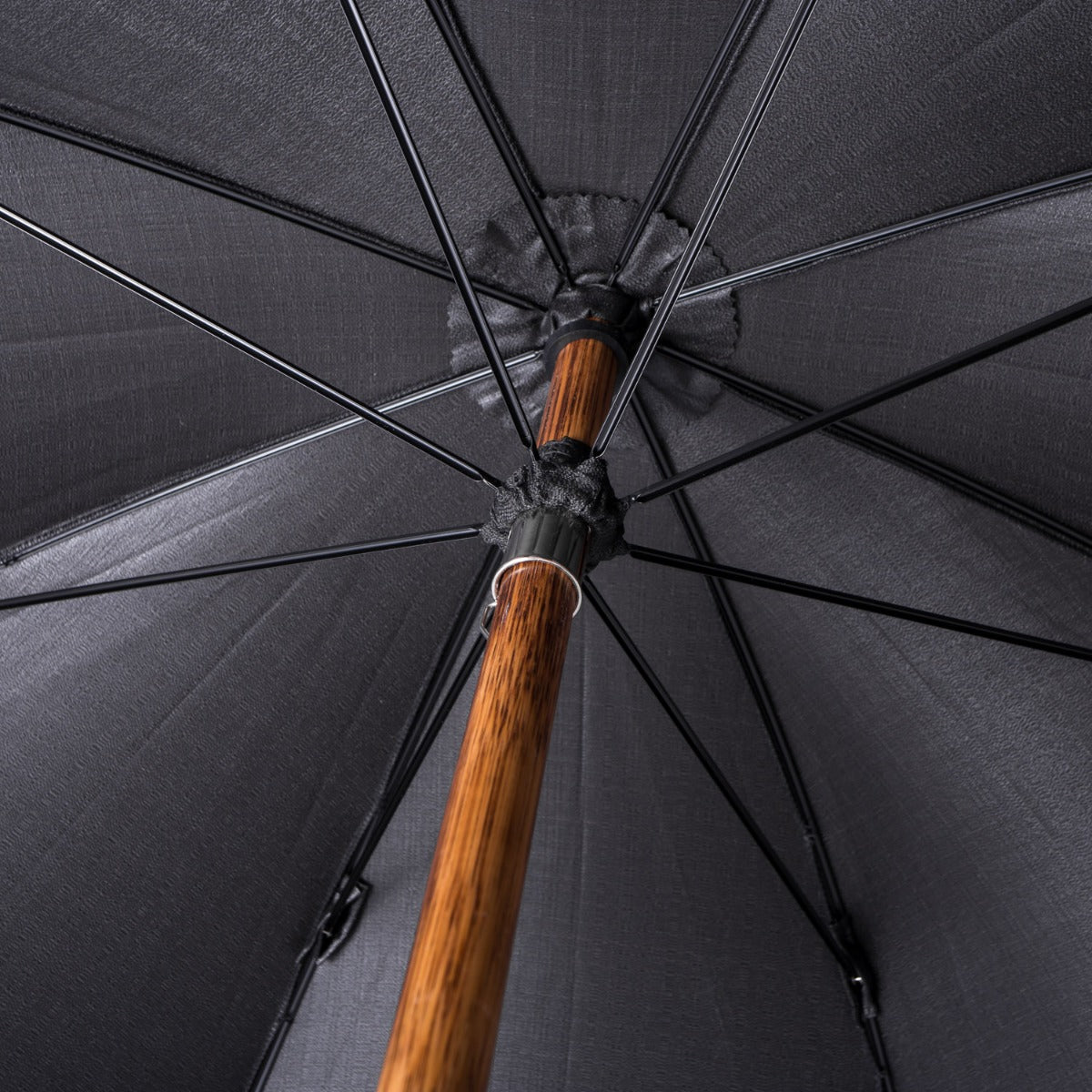 A close up of a Manila Root Solid Stick umbrella with an Imperial Black Canopy and a wooden handle by KirbyAllison.com.
