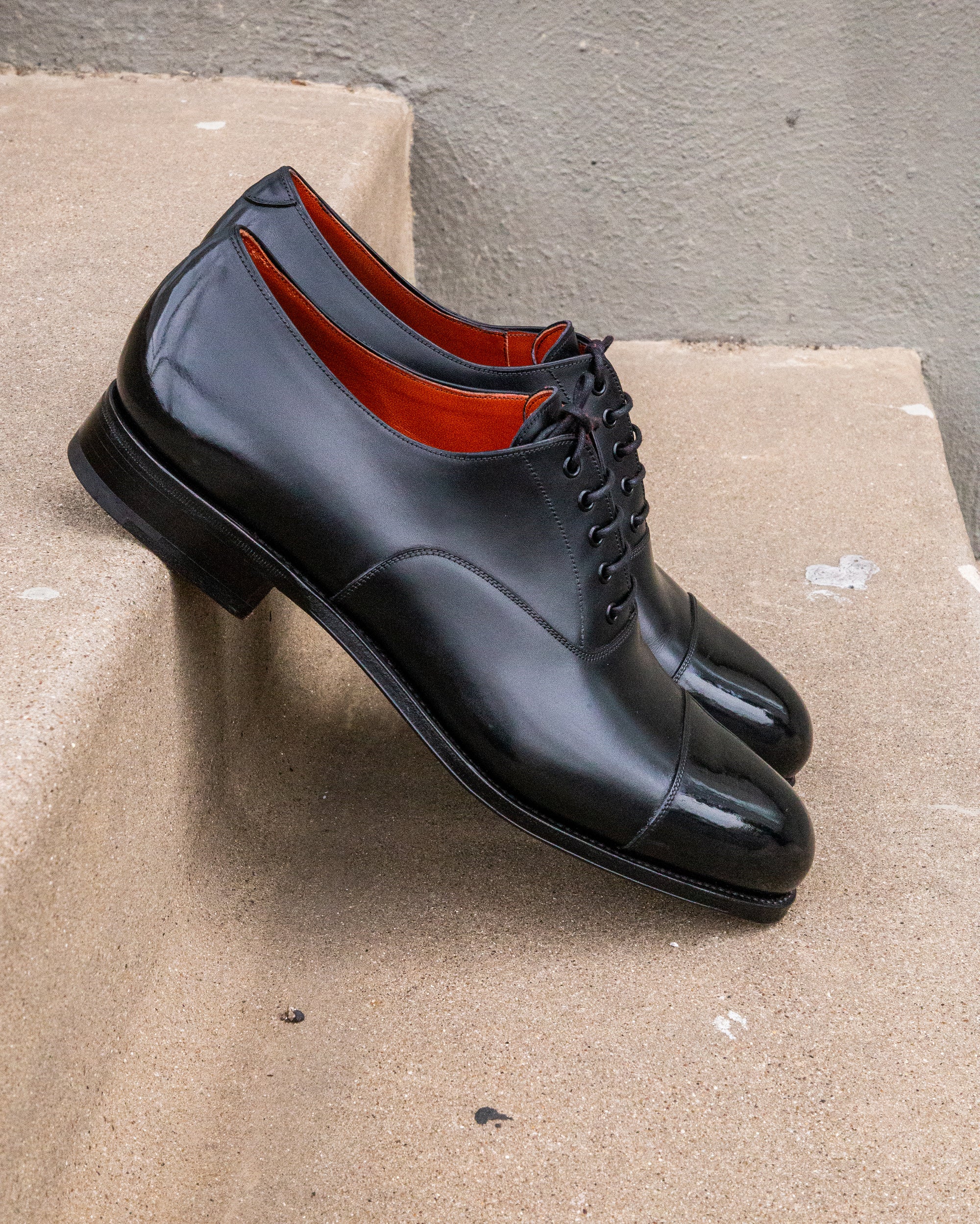 A pair of black oxford shoes with a High Shine Service, sitting on steps from KirbyAllison.com.