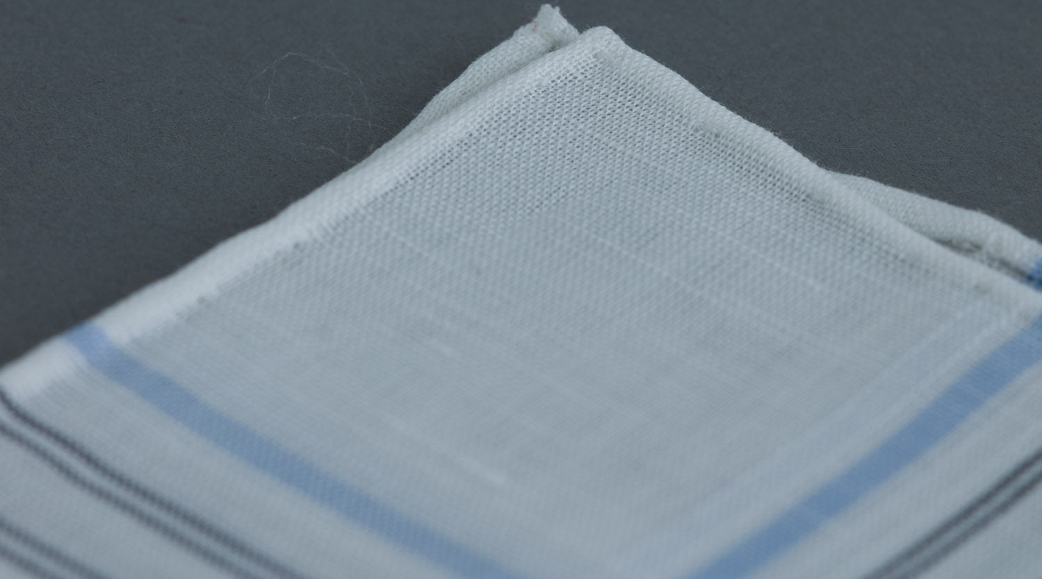 A close up of a Simonnot Godard Aran Pocket Square with hand-rolled edges.