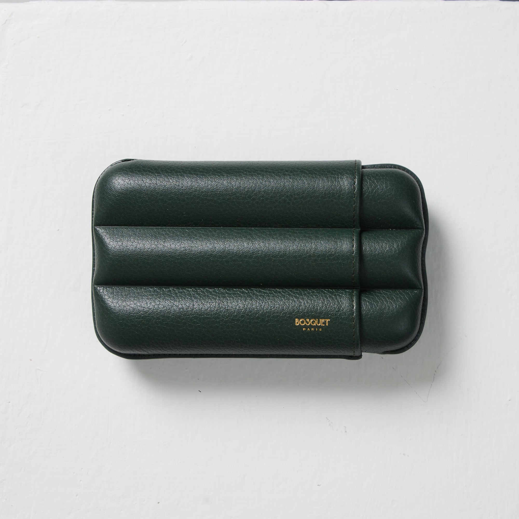 A green leather Bosque cigar case on a white surface.