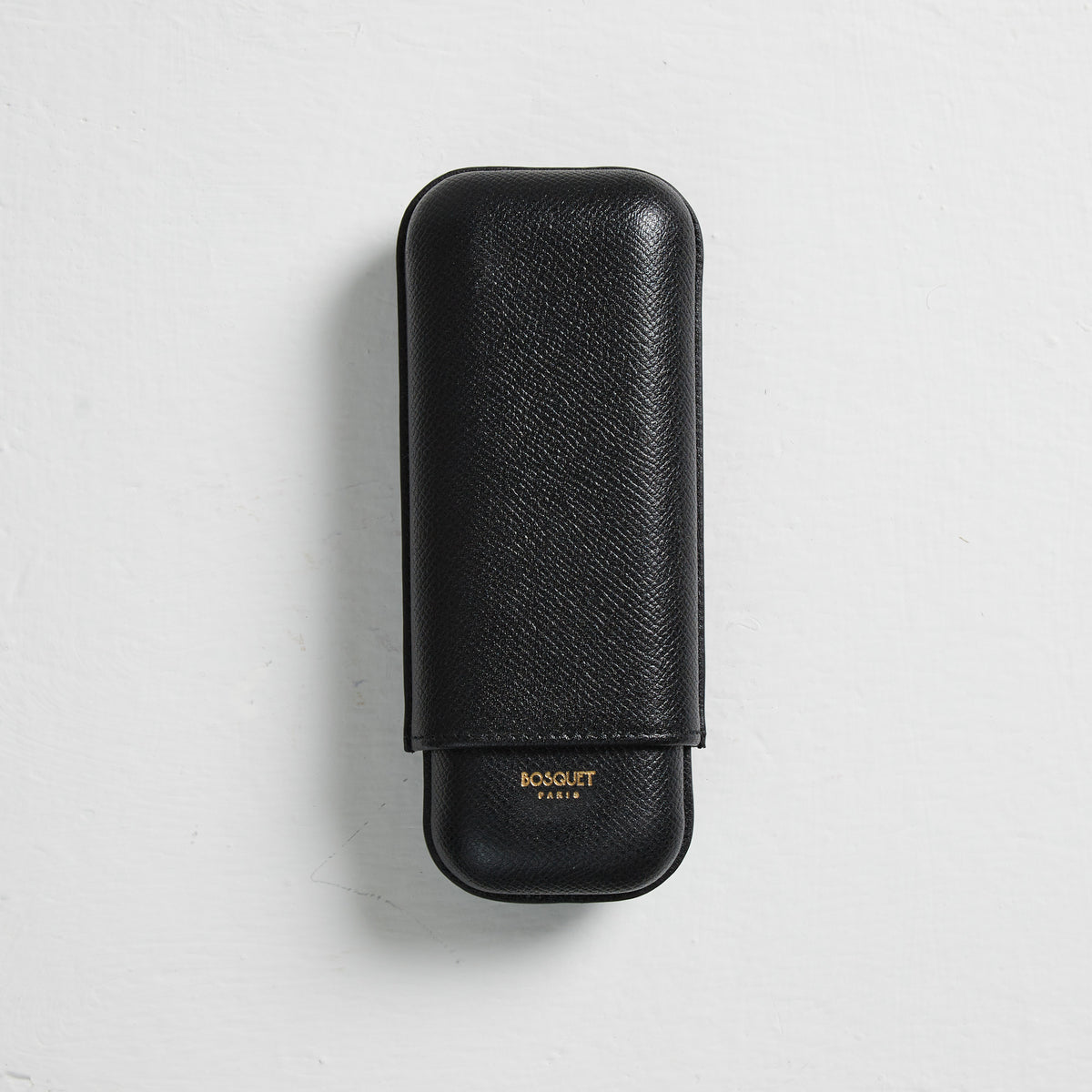A Bosque Smooth Black Leather Cigar Case on a white wall in France.