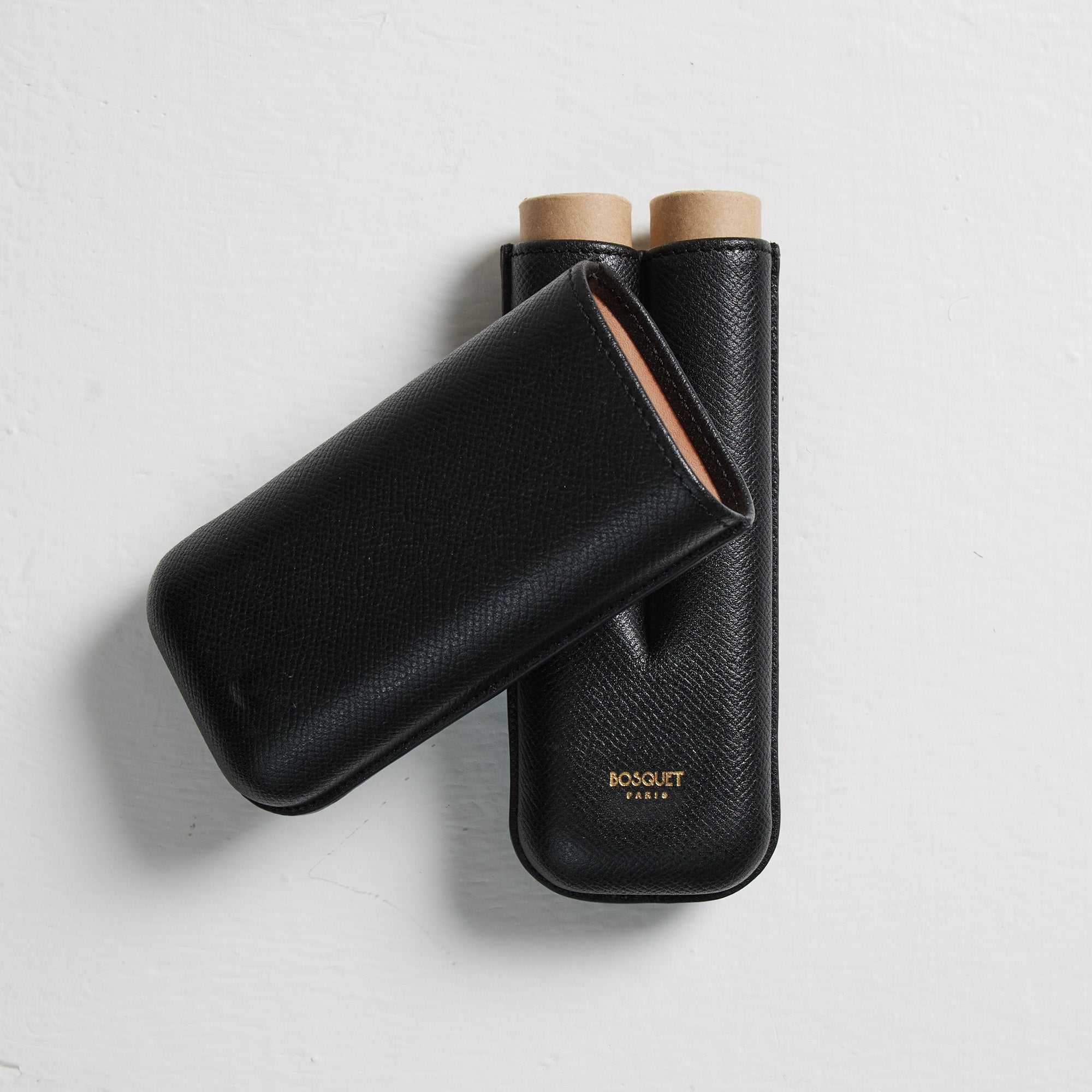 A pair of Bosque Smooth Black Leather Cigar Cases on a white surface.