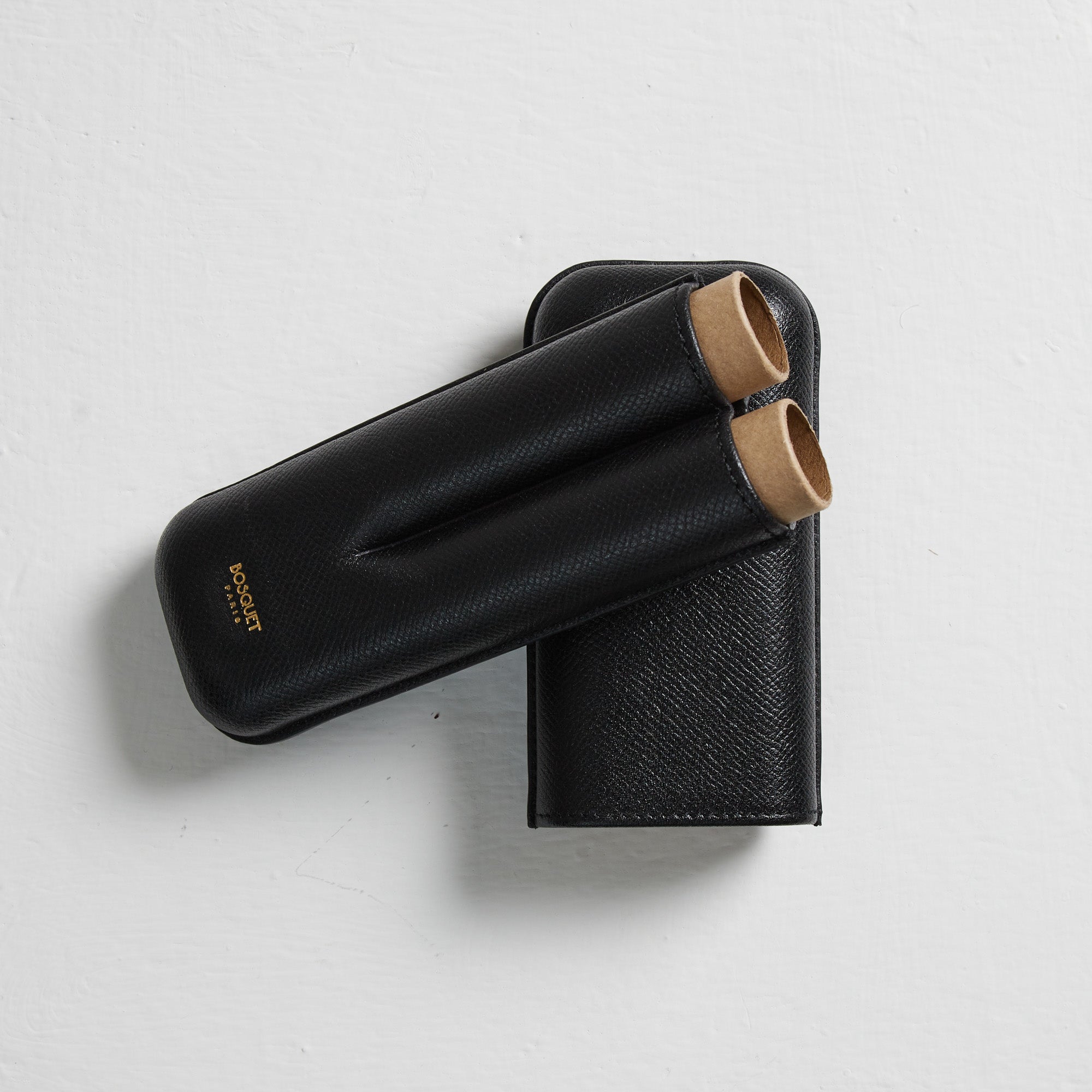 Two Bosque Smooth Black Leather Cigar Cases on a white surface.