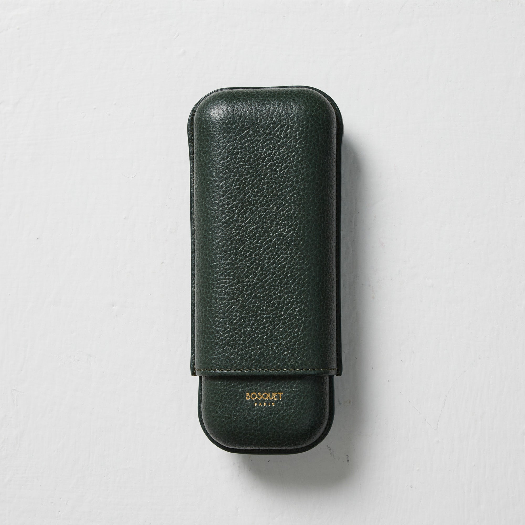 A Bosque Smooth Forest Green Leather Cigar Case for transporting cigars on a white surface.