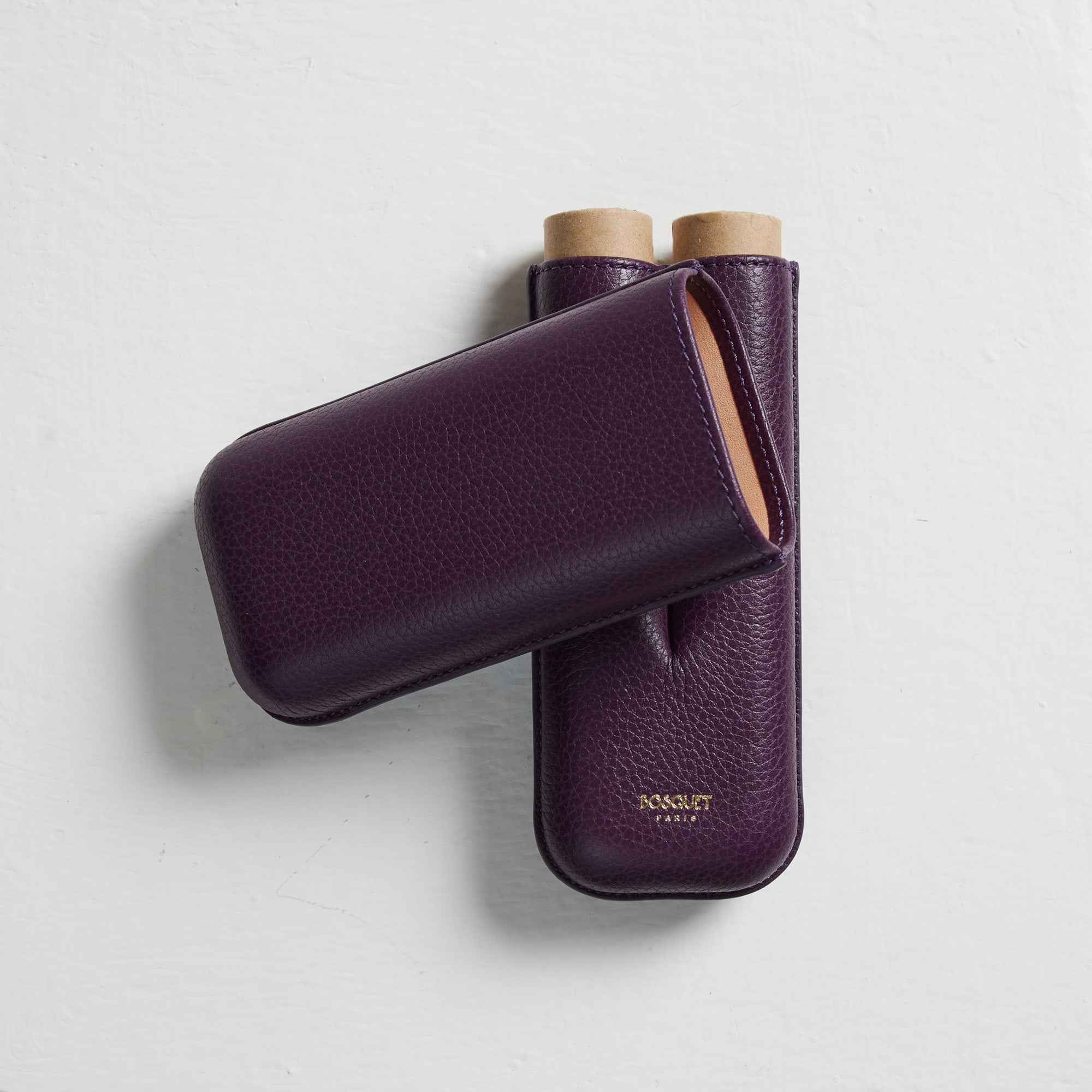 A pair of Bosque Smooth Purple Leather Cigar Cases on a white surface.