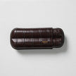 A Bosque Bosquet Crocodile Cigar Case, Dark Brown featuring five different layers on a white surface.