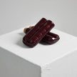 A pair of Bosquet Crocodile Cigar Case, Burgundy ice cream cups on top of a white cube showcasing Bosque crocodile leathers.