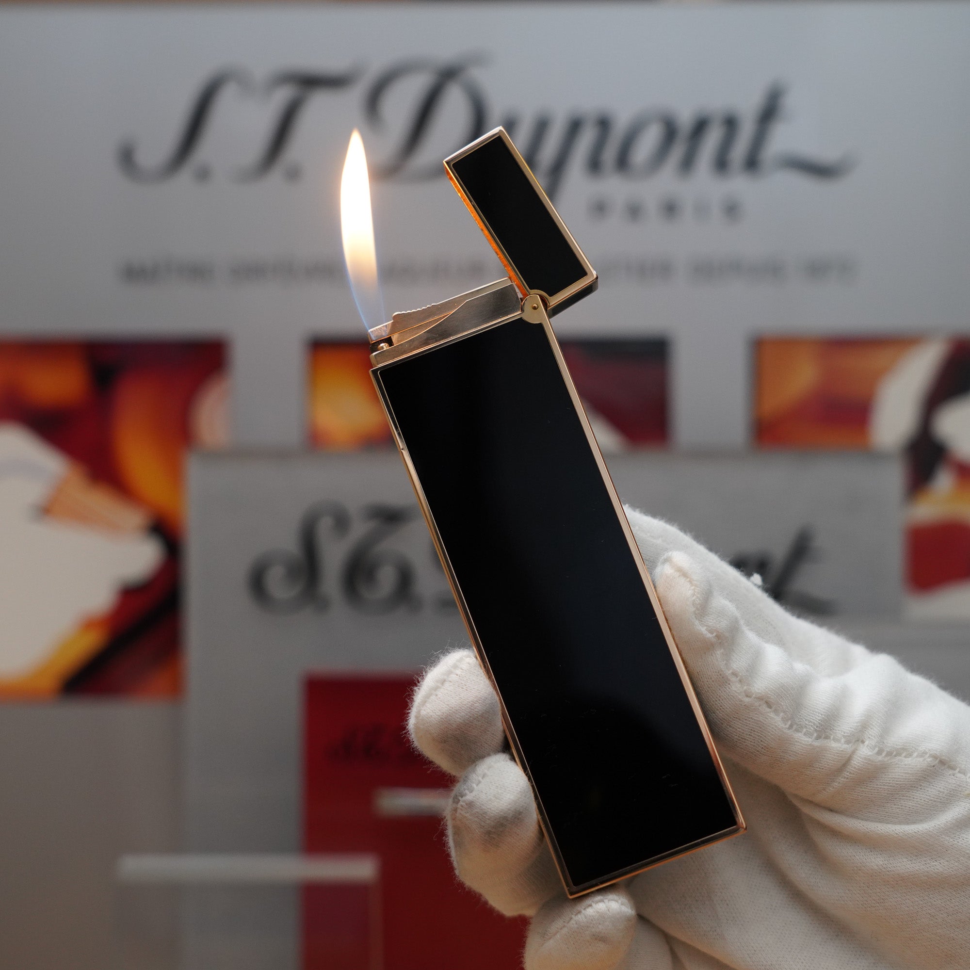 A person is holding a vintage 1980 S.T. Dupont 18k Gold Plated Ligne 2 Black Lacquer Table Lighter in front of a St. Dumont sign.