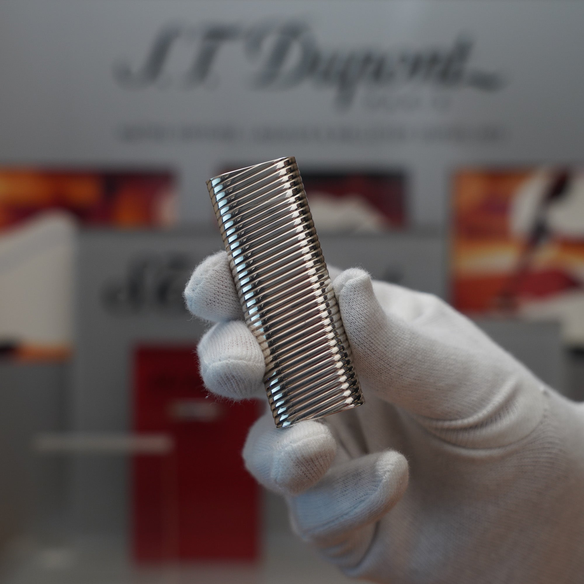 A person holding a Vintage 1980 Cartier Solid Silver 925 Lighter Factory Argent (Torsade) comb in front of a display.