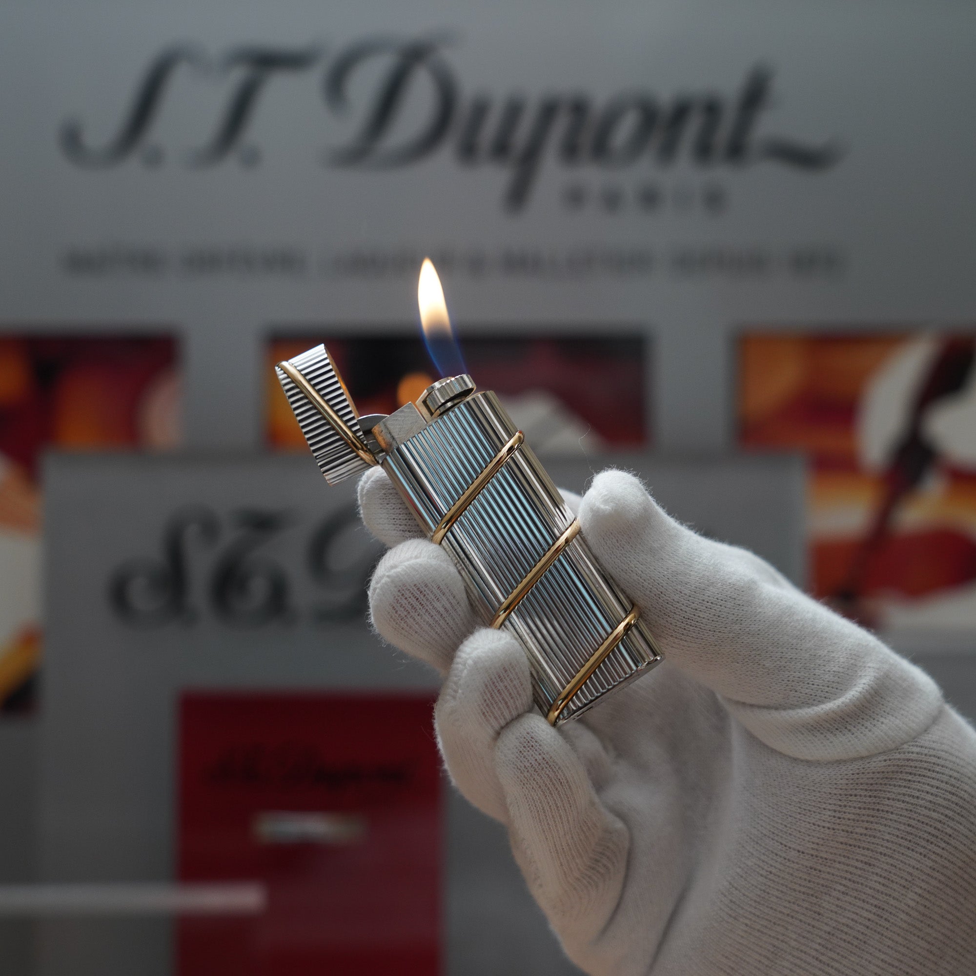A person is holding a Cartier vintage lighter in front of a sign that says st dupont.