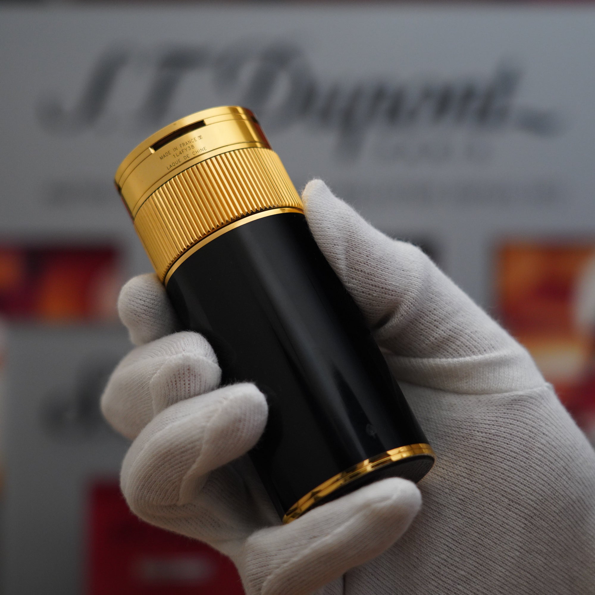 A person showcasing a Vintage 1980 S.T. Dupont 18k Unique Cylinder Gold Plated Black Lacquer Dual Flame Table Lighter in black and gold.