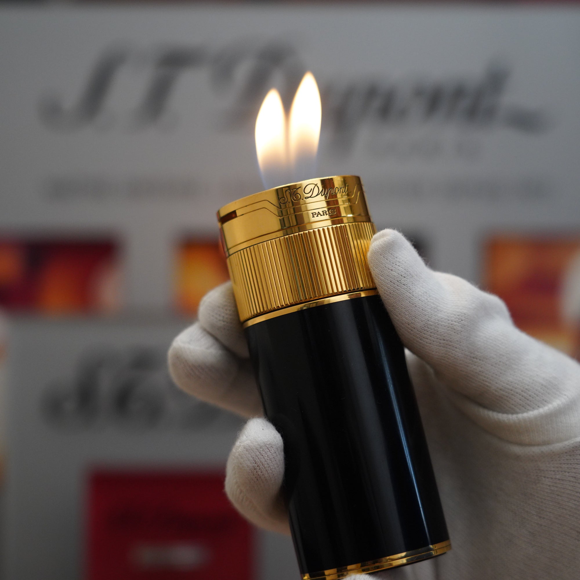 A person holding a vintage S.T. Dupont Vintage 1980 S.T. Dupont 18k Unique Cylinder Gold Plated Black Lacquer Dual Flame Table Lighter table lighter.