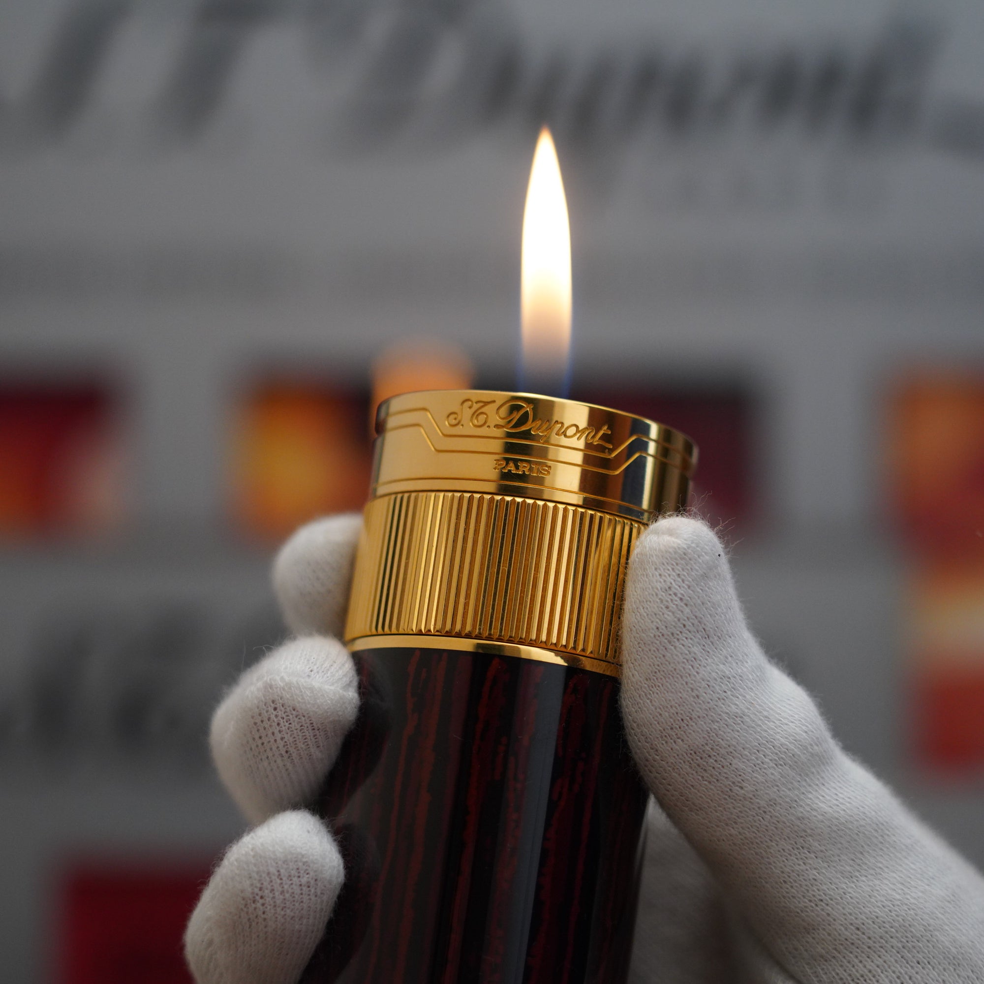 A person is holding a Vintage 1980 S.T. Dupont 18k Masterpiece Unique Cylinder Gold Plated Macassar Lacquer Dual Flame Table Lighter in their hand.