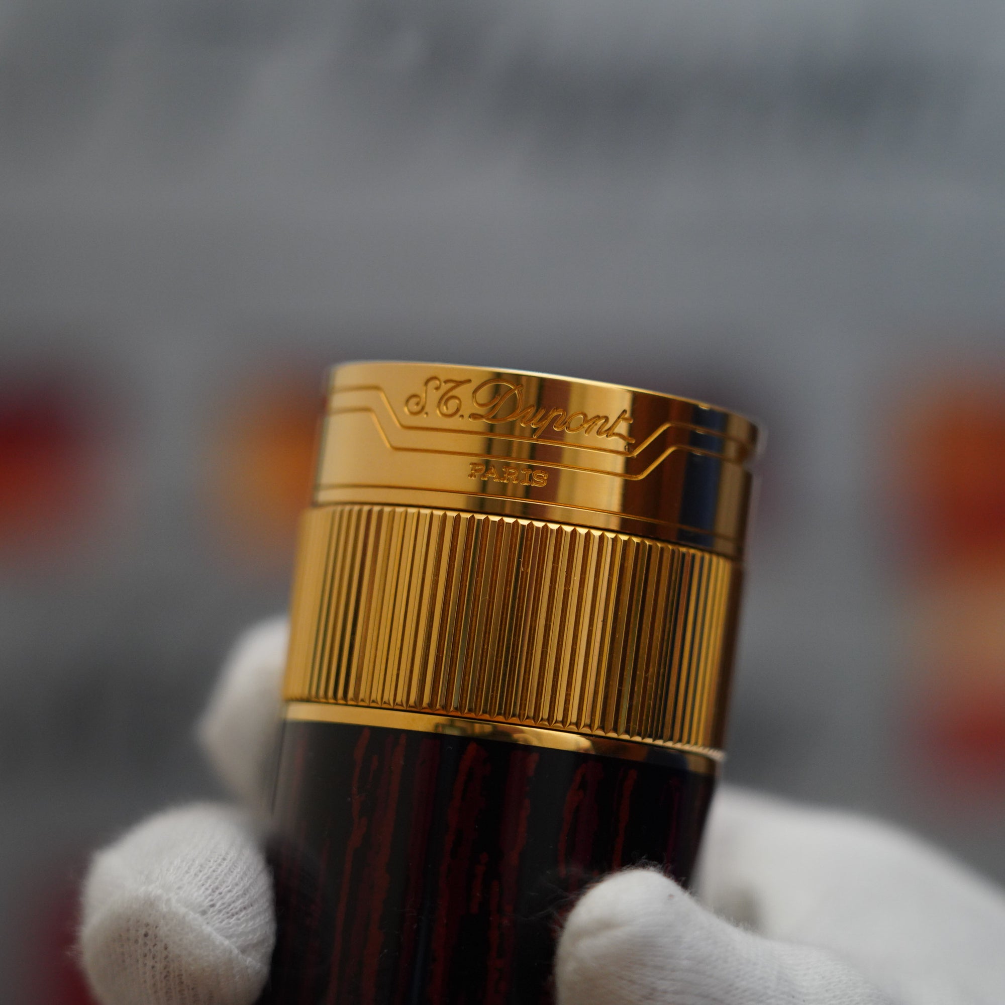 A person is holding a vintage S.T. Dupont 1980 18k Masterpiece Unique Cylinder Gold Plated Macassar Lacquer Dual Flame Table Lighter.