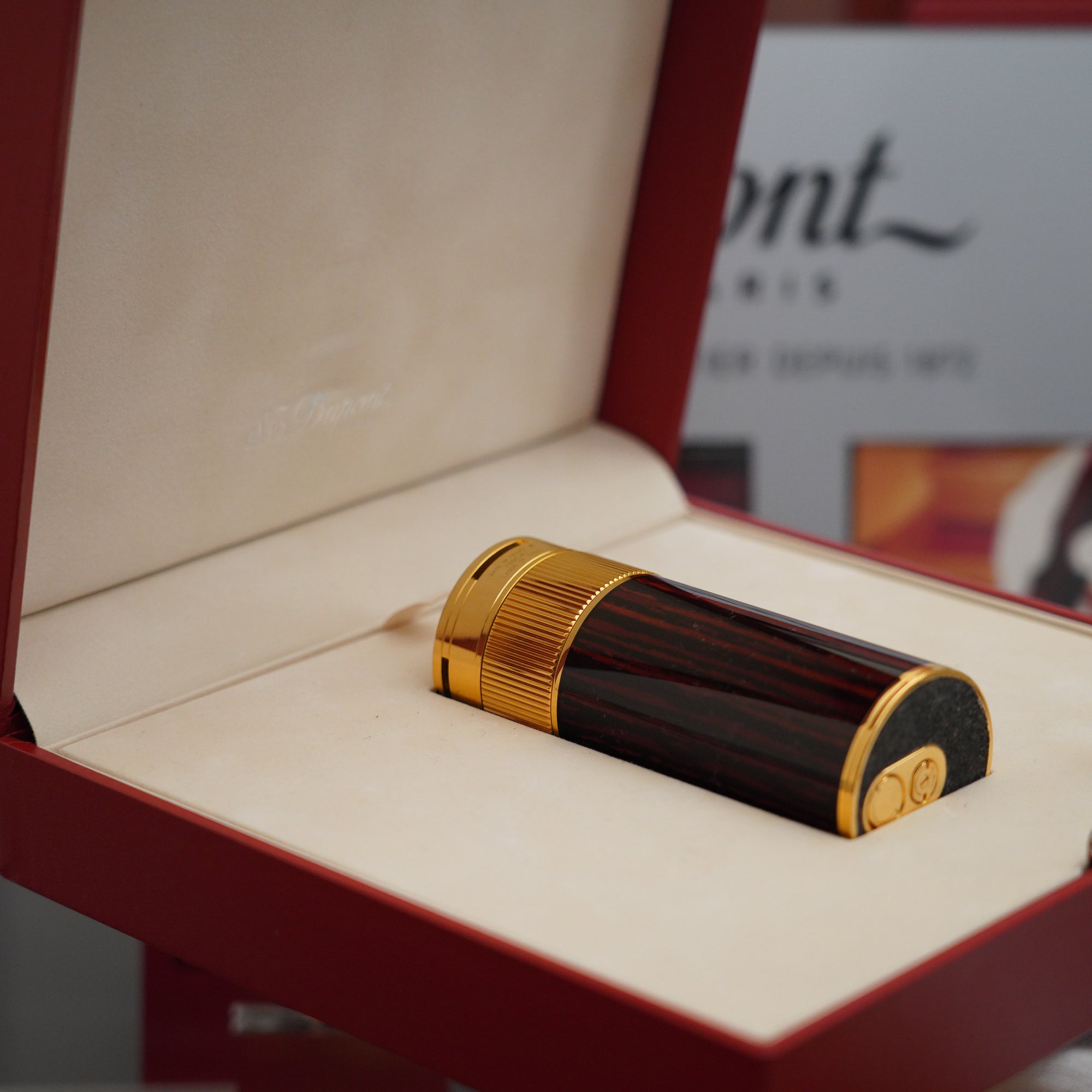 A Vintage 1980 S.T. Dupont 18k Masterpiece Unique Cylinder Gold Plated Macassar Lacquer Dual Flame Table Lighter is sitting in a box.