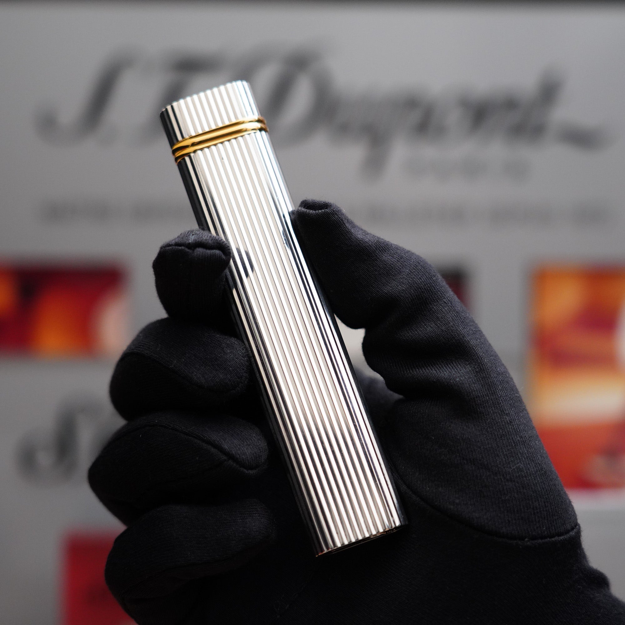 A vintage man holding a Vintage 1980 Cartier Vertical Lines Silver Plated Table Lighter iconic Trinity Ring Lighter in his hand.