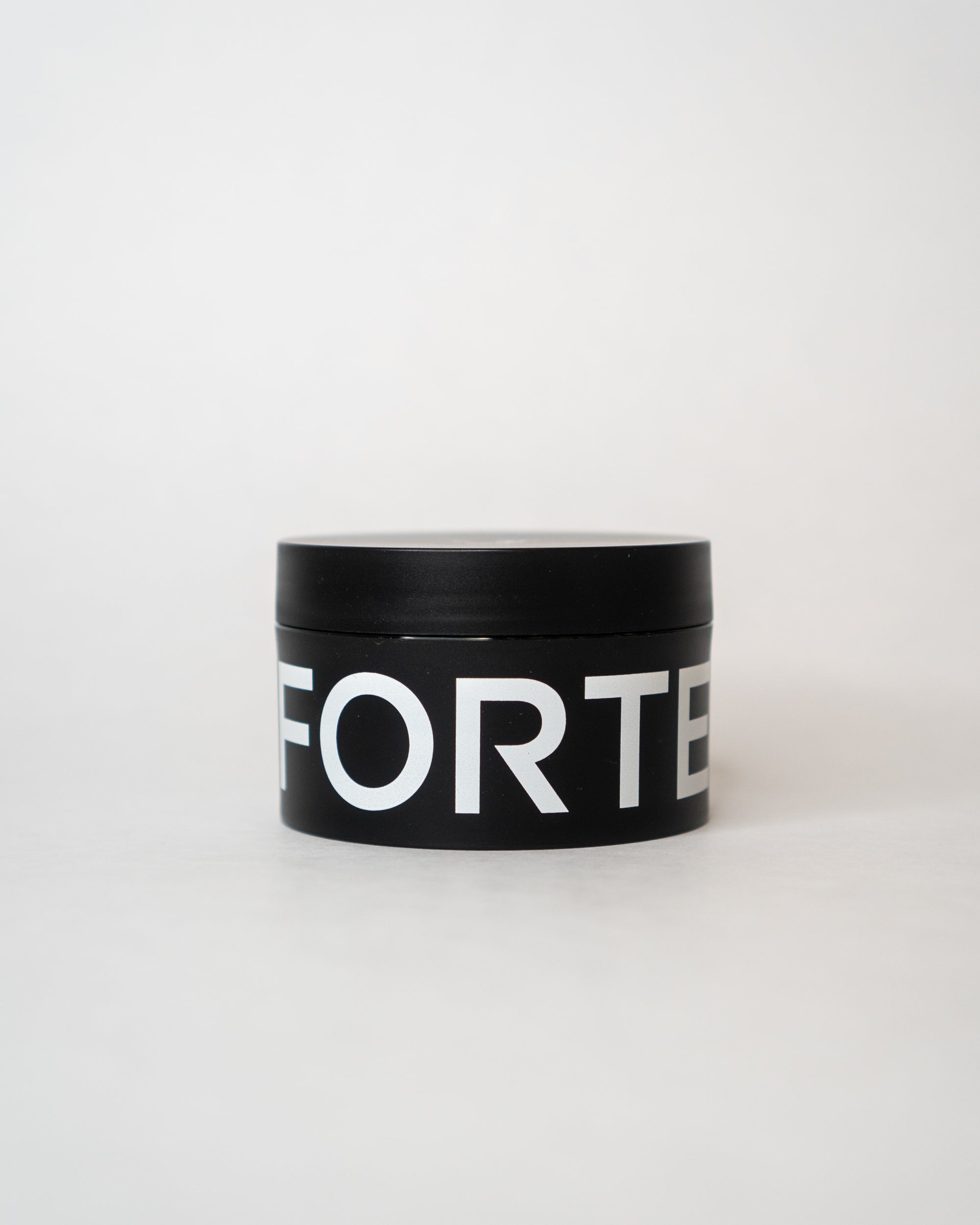 A nourished and healthy black tin with the word Forte Series Pomade by KirbyAllison.com on it, perfect for high volume hairstyles.