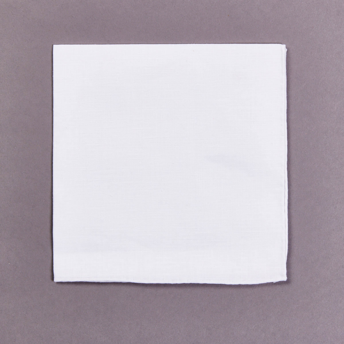 A Simonnot Godard 100% Linen Plain White Pocket Square on a gray background.