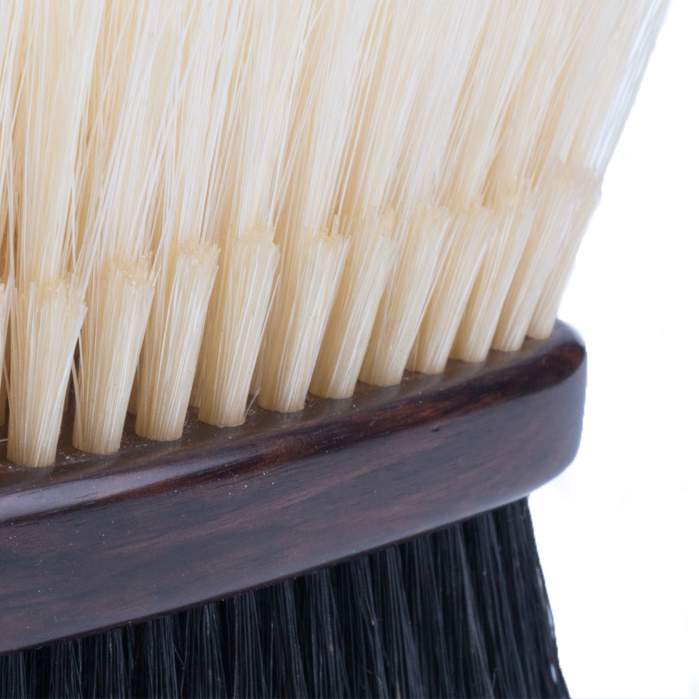 A close up of the KirbyAllison.com Ebony Deluxe Double-Sided Garment Brush with black and white bristles.