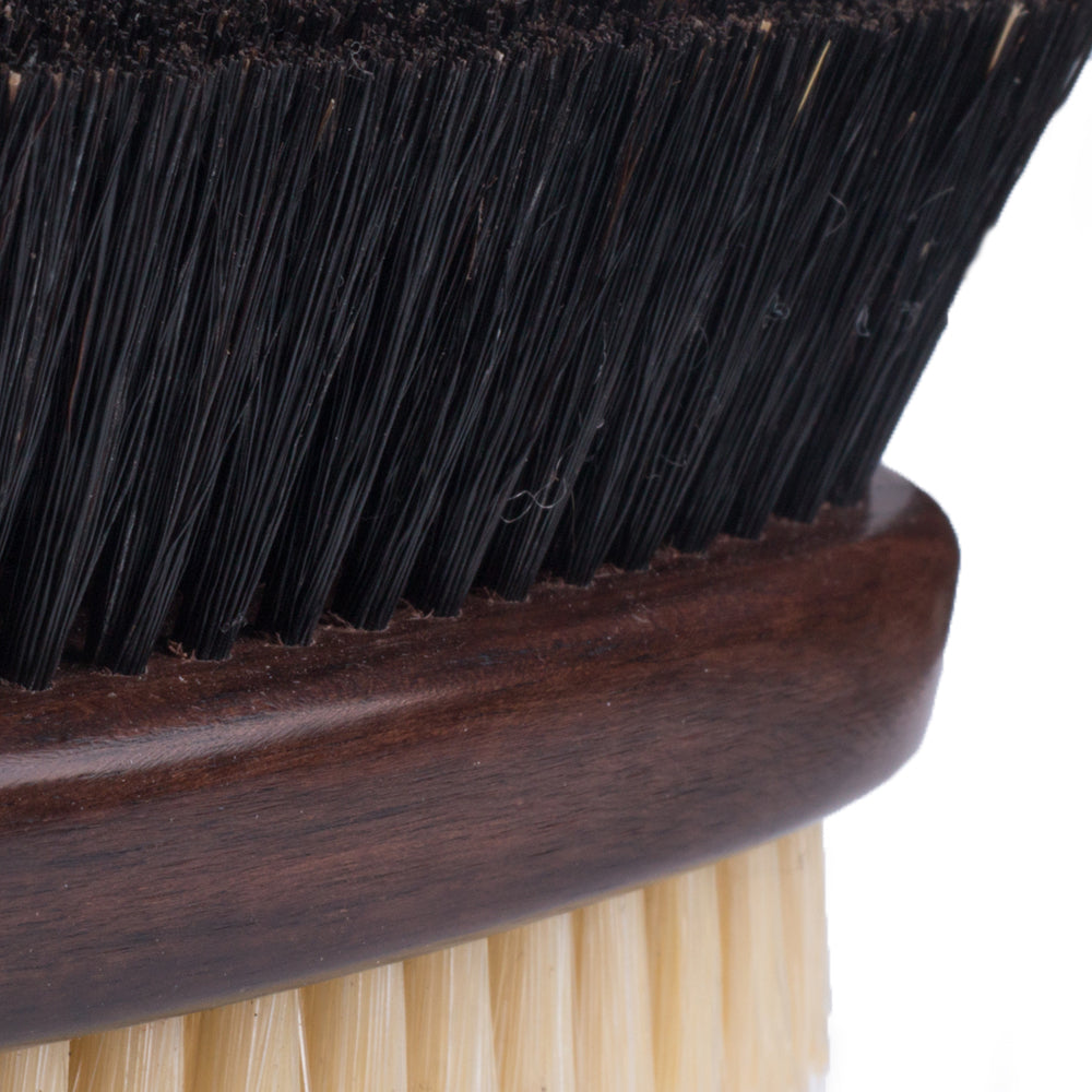 A close up of a KirbyAllison.com Ebony Deluxe Double-Sided Garment Brush.