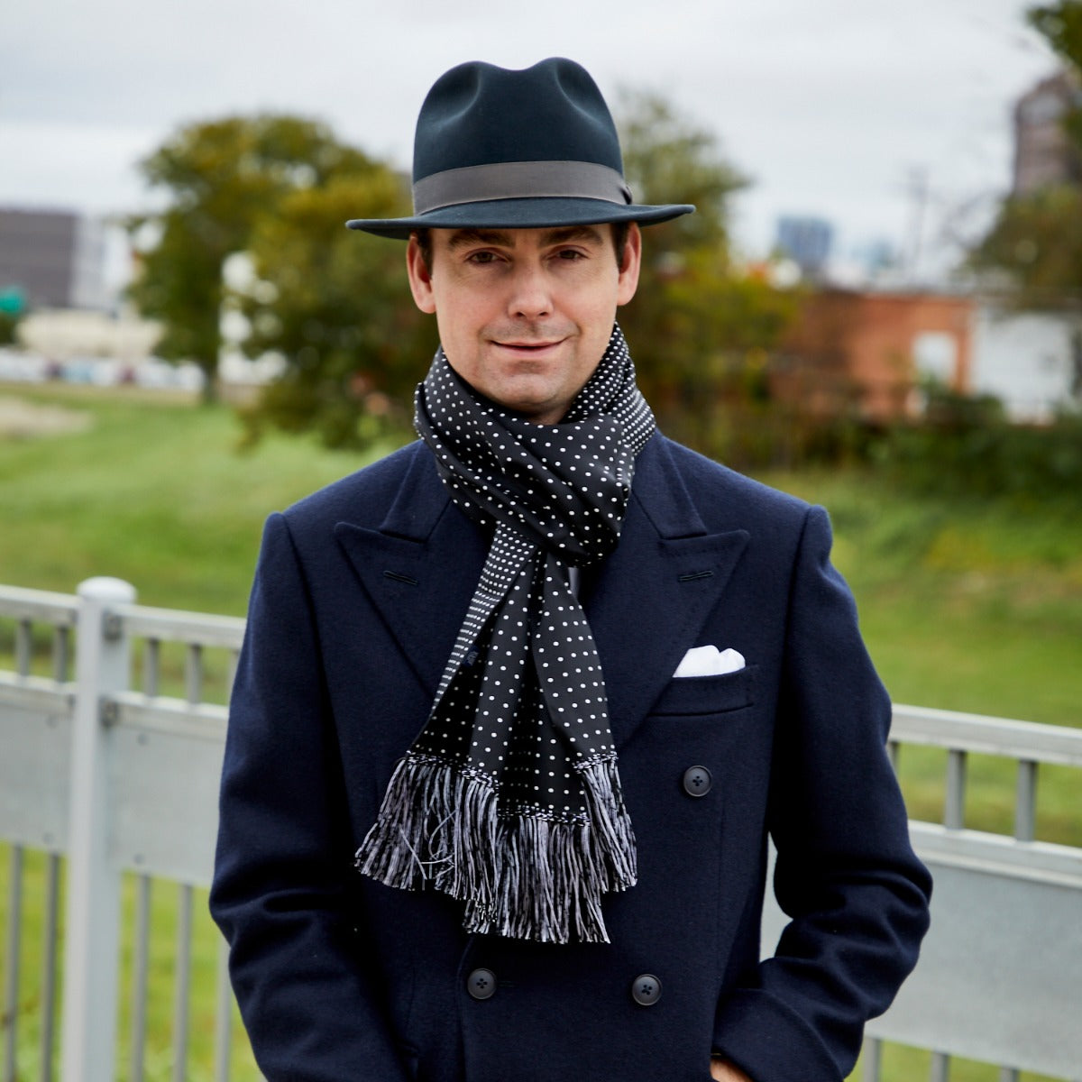 A man wearing a hat and Sovereign Grade Black London Dot 36oz Reversible Printed Silk Scarf by KirbyAllison.com in England.