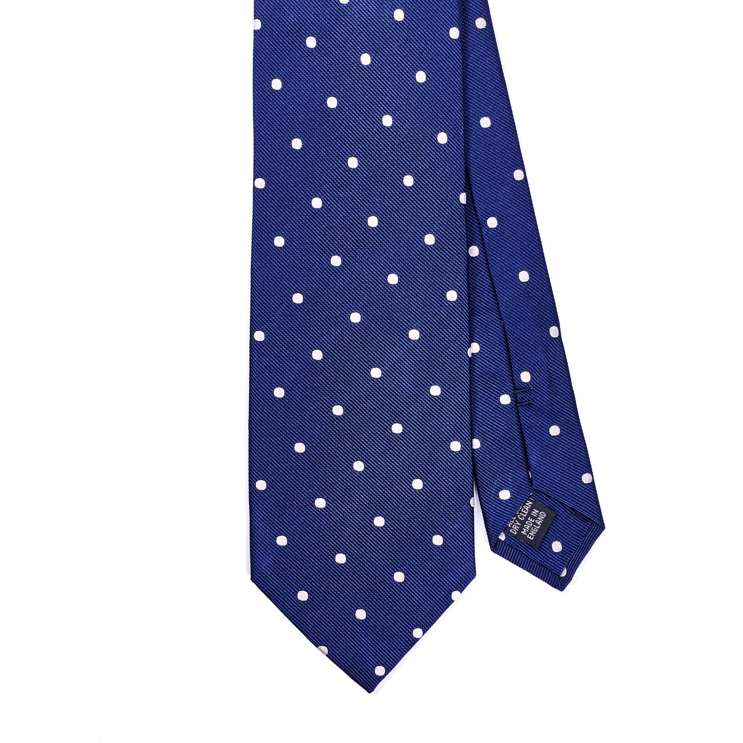 A blue and white polka dot KirbyAllison.com Sovereign Grade Woven Navy/White Wide Dot Tie on a white background, handmade in the United Kingdom.