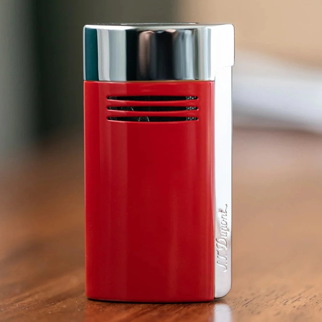 An S.T. Dupont Red and Chrome Megajet Lighter sitting on top of a wooden table.