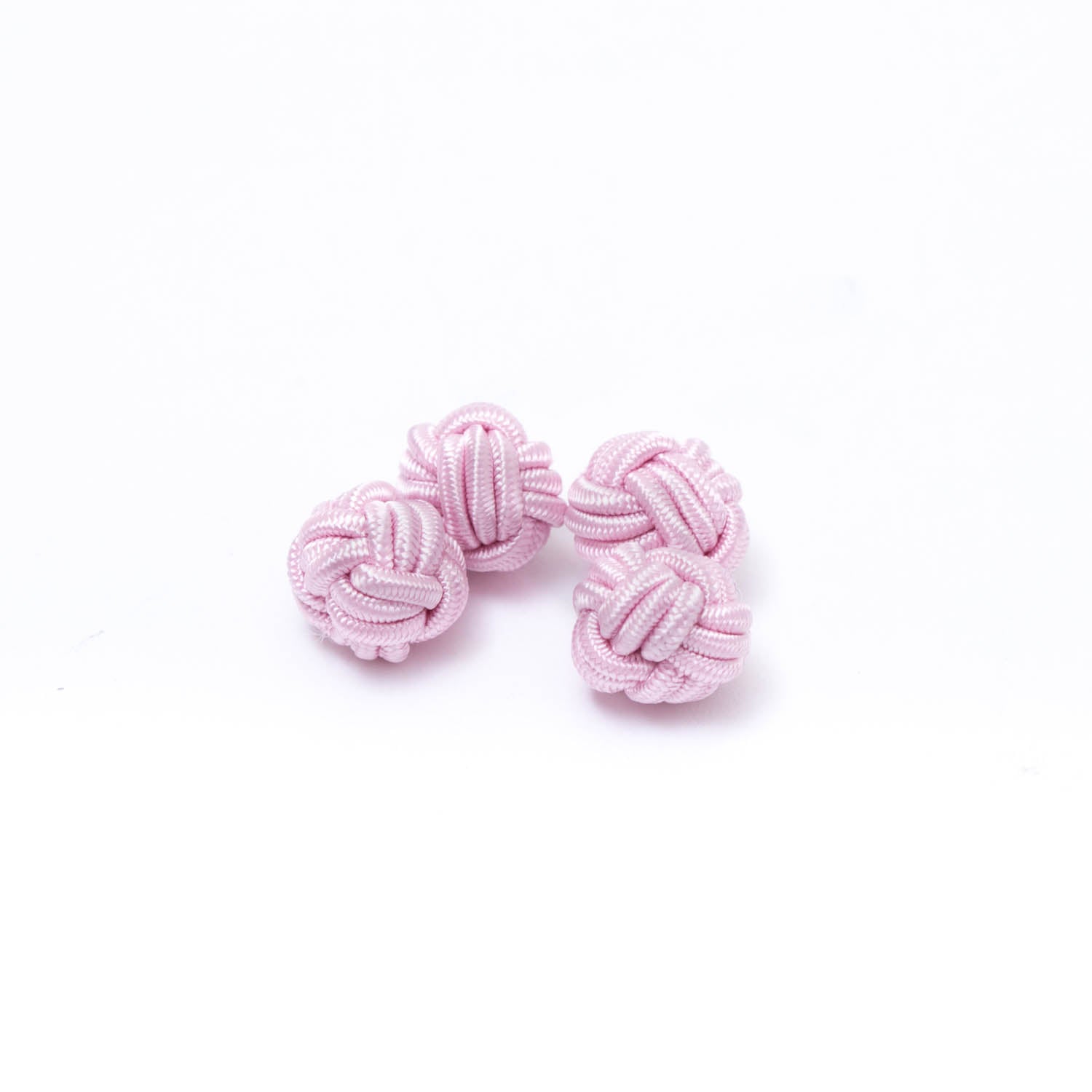 A group of handmade pink knotted Solid Knot Cuff Links by KirbyAllison.com on a white surface.