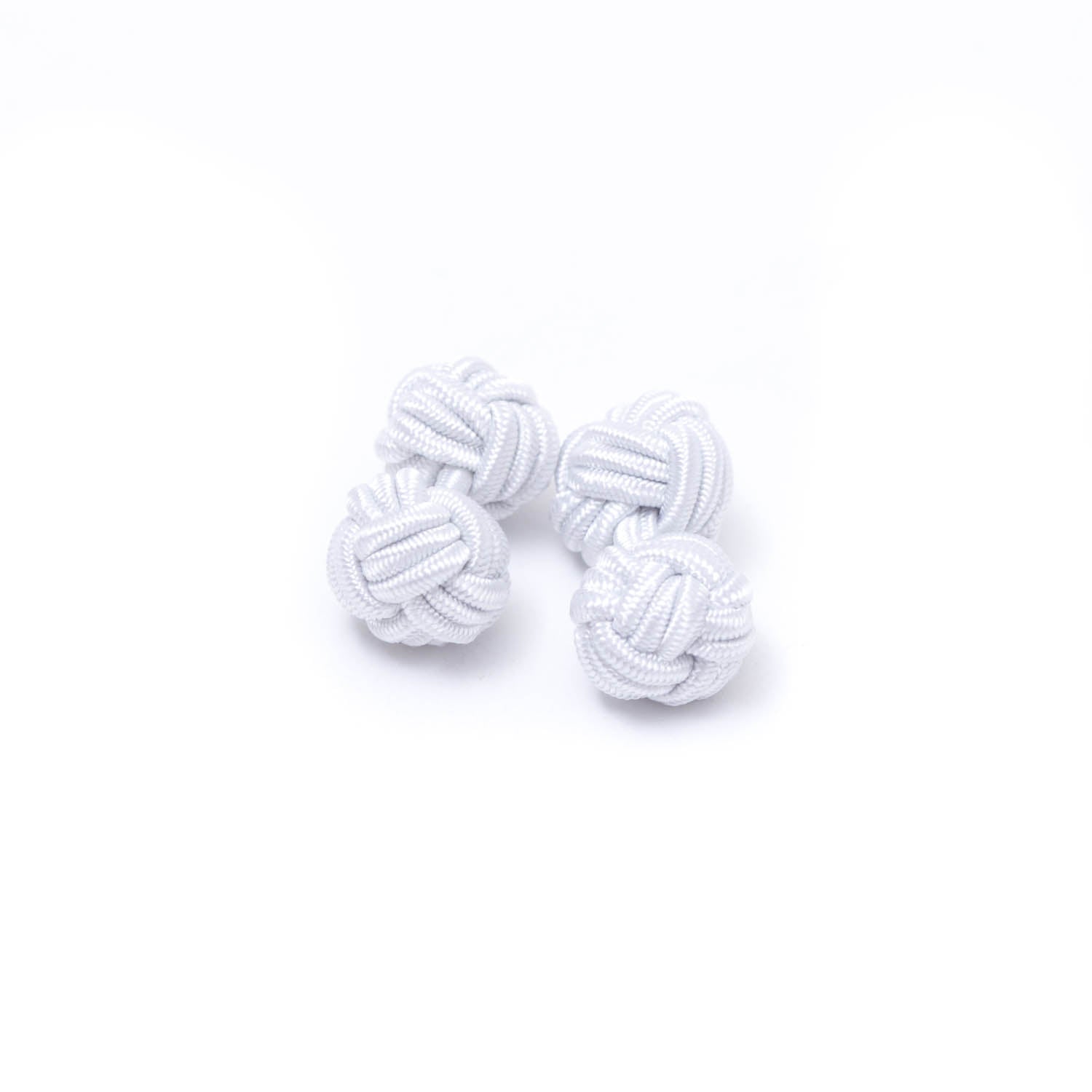 Two Solid Knot Cuff Links by KirbyAllison.com on a white surface.
