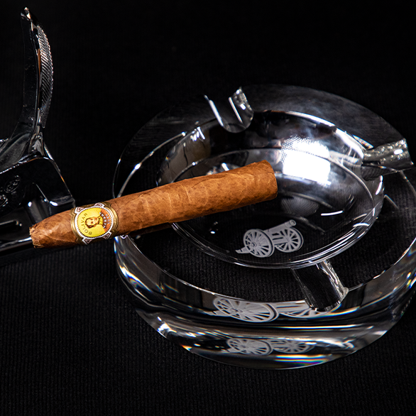 A smoking accessory with a finer cigar in a Kirby Allison.com glass ashtray.