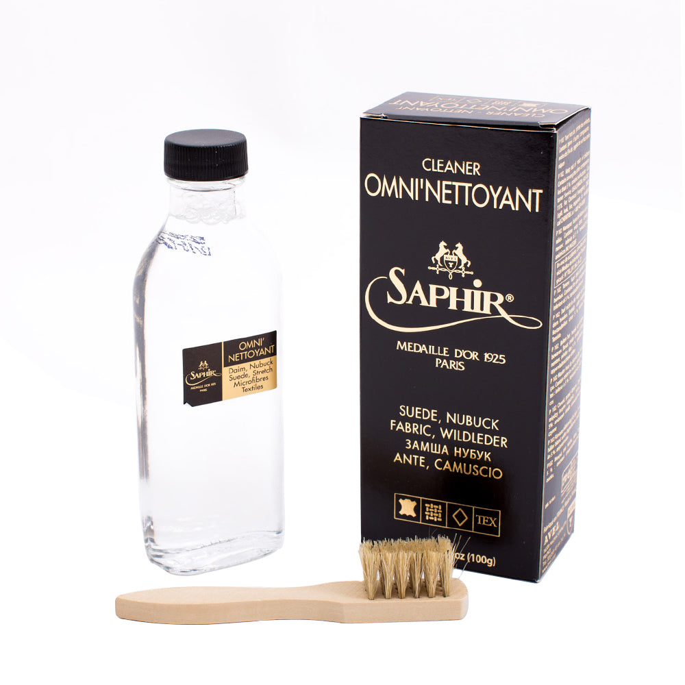 A bottle of Saphir Omni'Nettoyant Suede Shampoo, a brush, and a stain remover.
