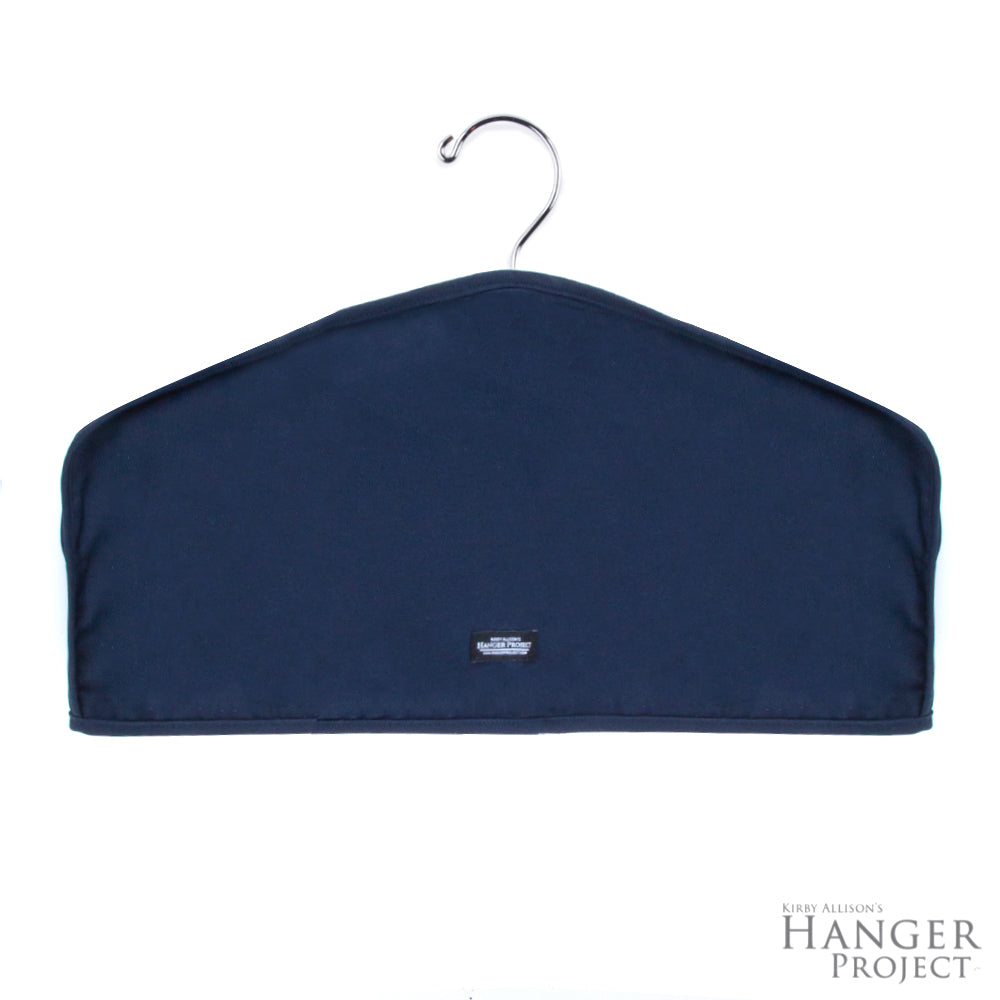 A Deluxe Cotton Twill Dust Cover with a black label on it, perfect for organizing garments in a closet.