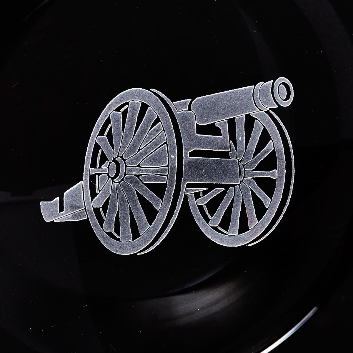A black plate with an image of a cannon, perfect as a smoking accessory for finer cigars is the Kirby Allison Glass Cigar Ash Tray - Round from KirbyAllison.com.
