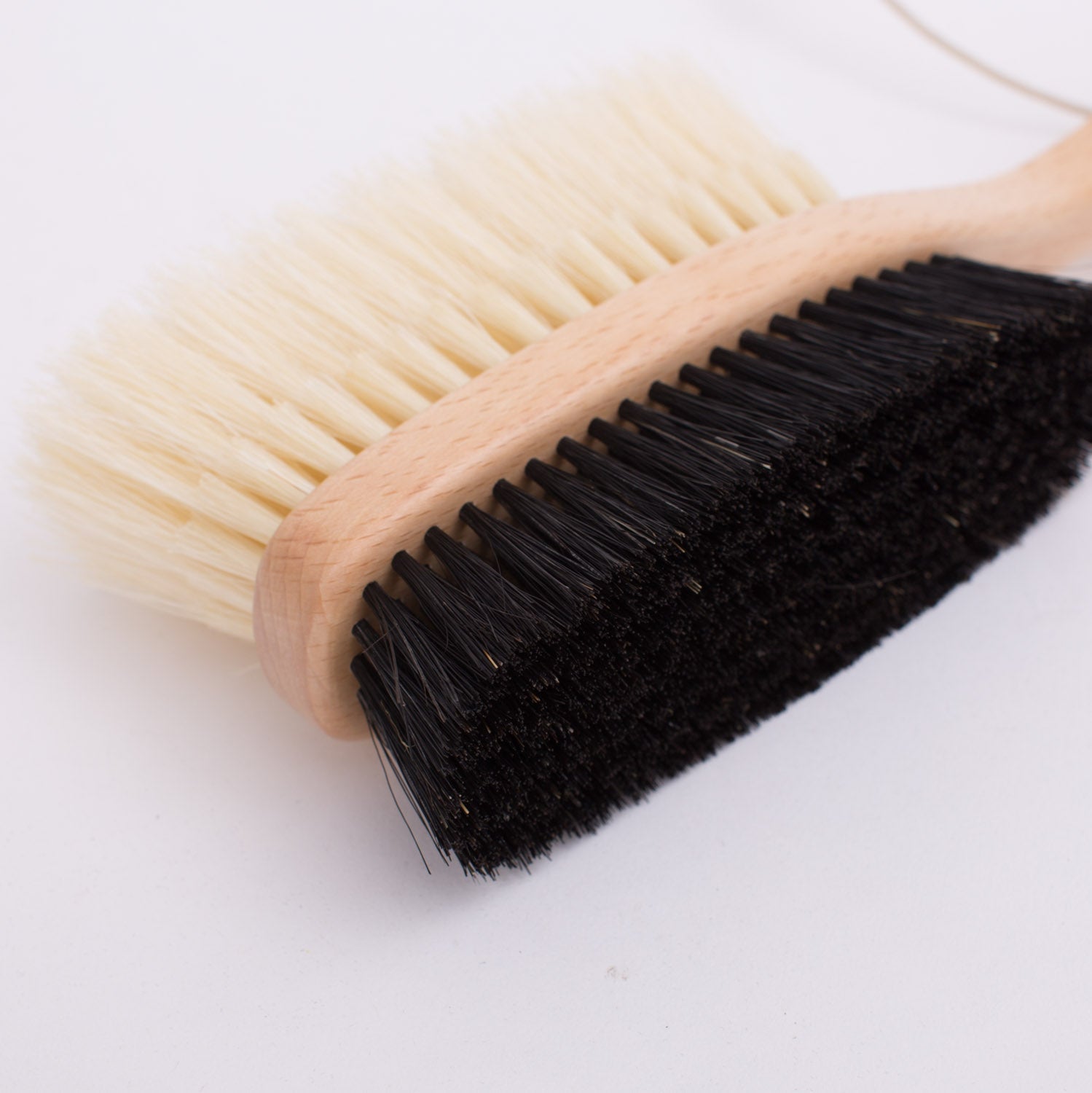 A KirbyAllison.com Hanger Project Deluxe Double-Sided Garment Brush with black bristles on a white surface.