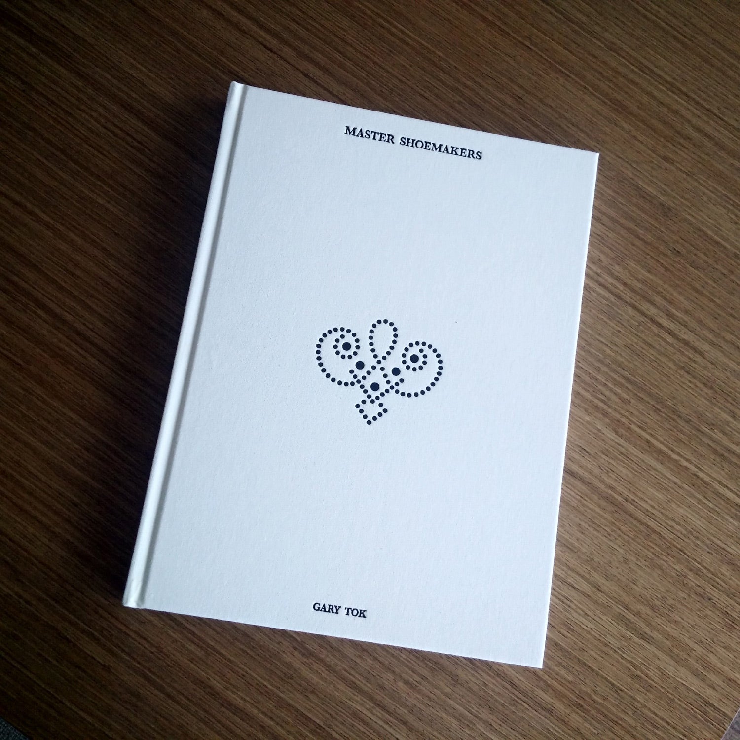 A "Master Shoemakers: The Art and Soul of Bespoke Shoes" book with a drawing of a flower on it.