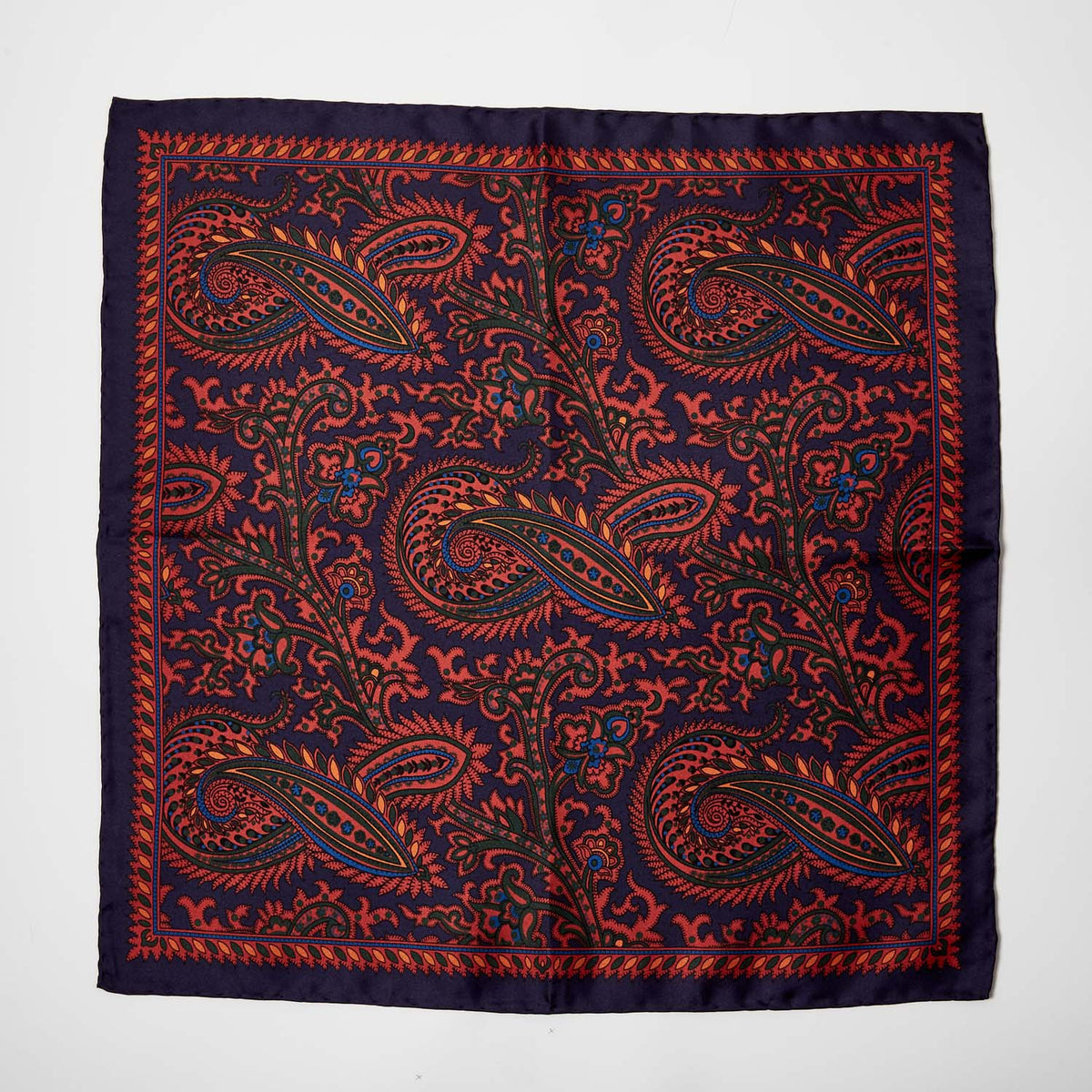 A Sovereign Grade 100% Silk Navy Pocket Square by KirbyAllison.com, featuring a blue and orange paisley pattern, perfect for adding formality to any outfit.