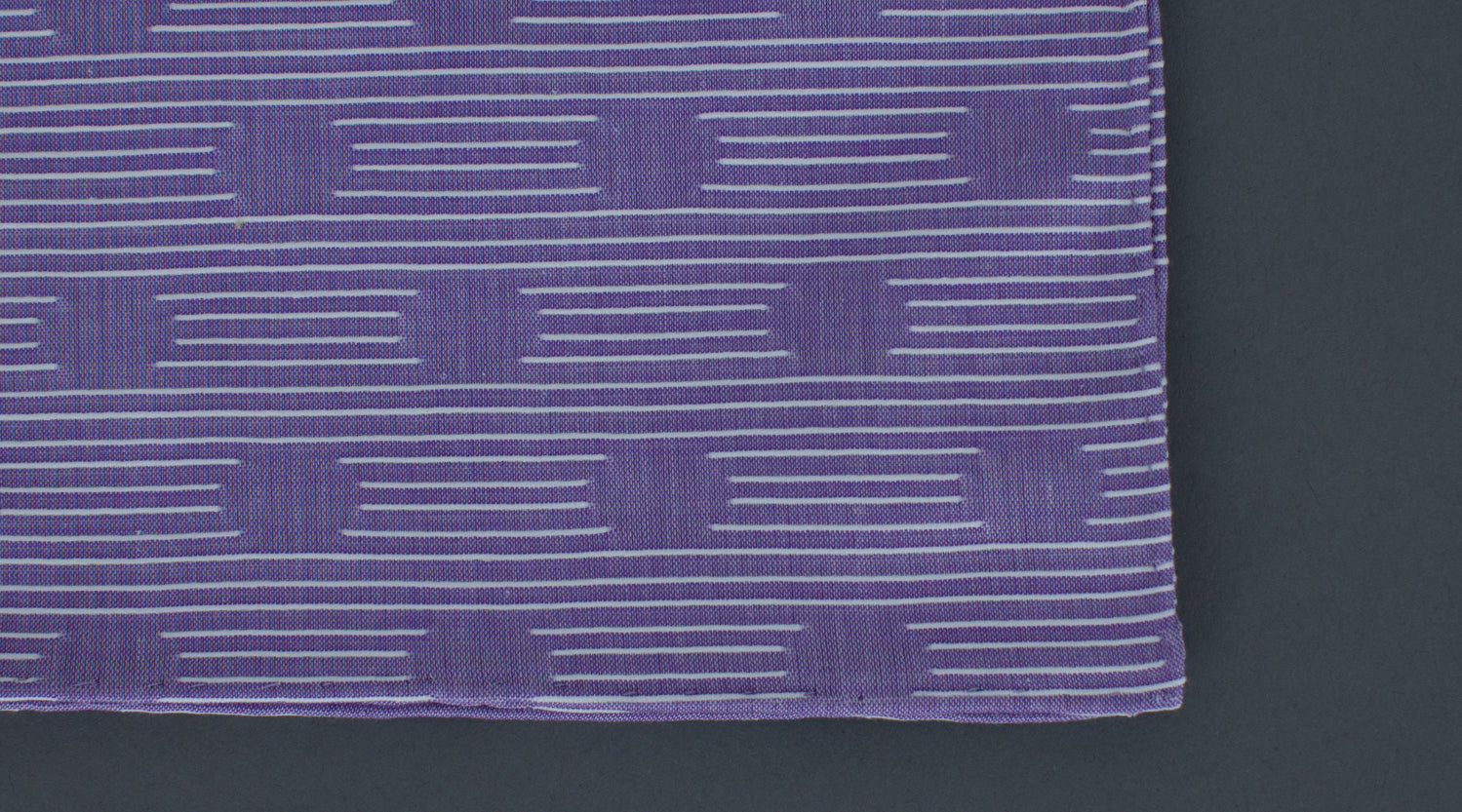 A high quality Simonnot Godard Violet Les Pois Fils Coupe Cotton Pocket Square, featuring purple and white stripes, resting on a sleek black surface.