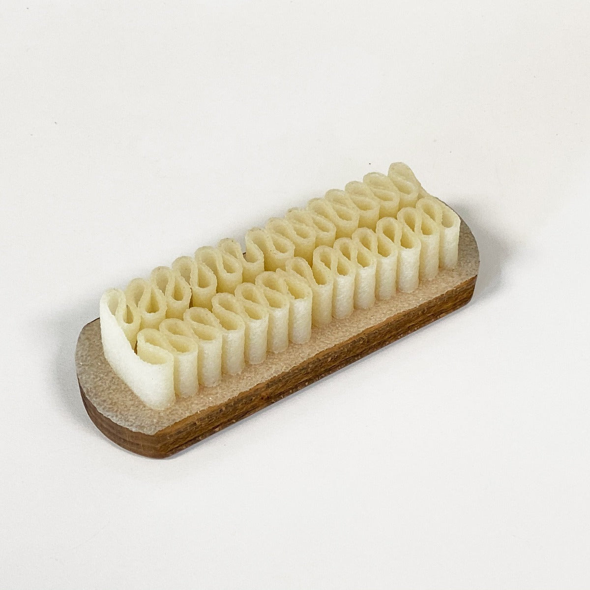 A white Wellington Crepe Brush for Suede and Nubuck bar on a white surface using natural rubber crepe brush by KirbyAllison.com.